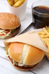 Photo of Delicious burgers and cola on light wooden table, closeup. Tasty fast food