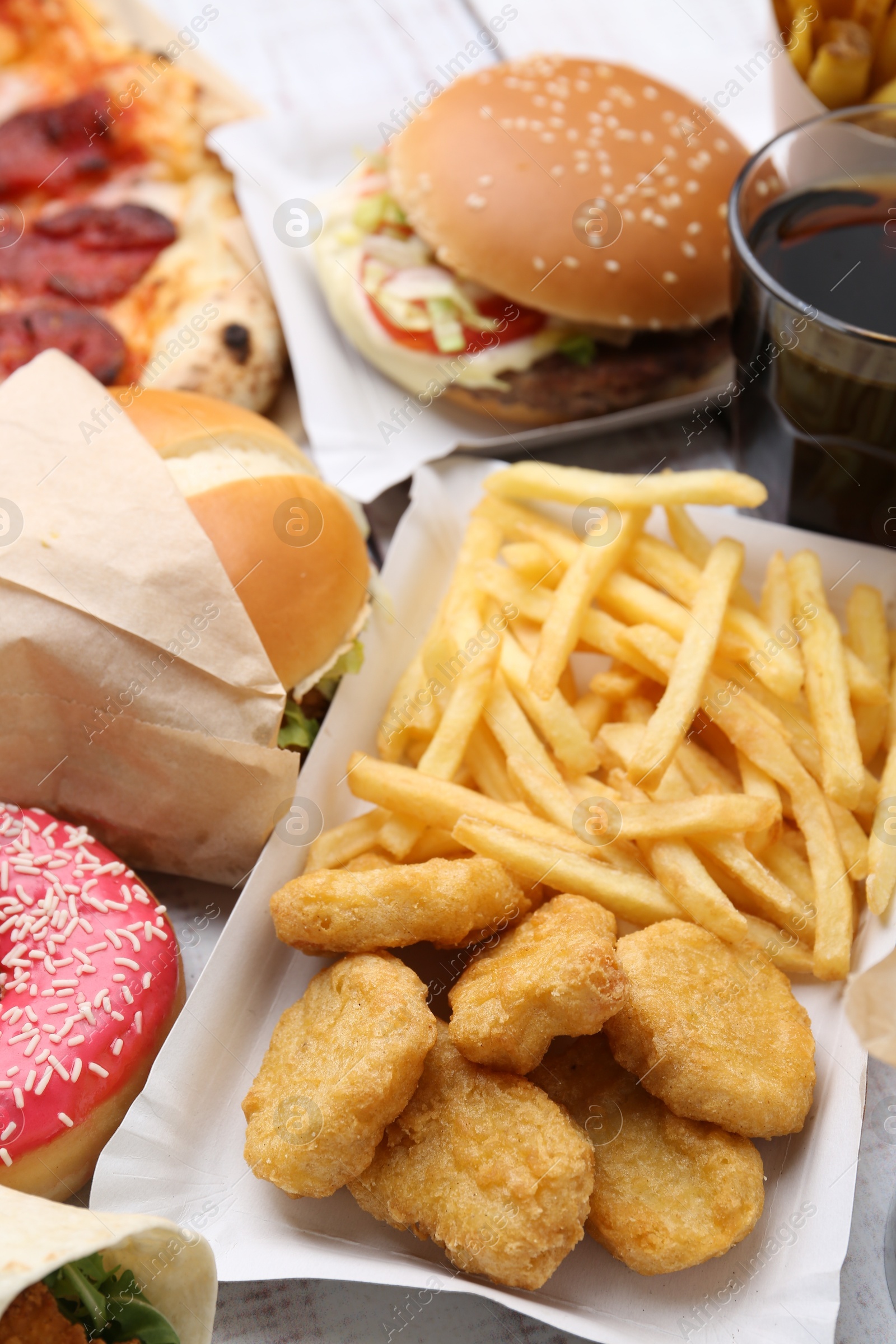 Different delicious fast food on light wooden table, closeup Photo of Different delicious fast food on light wooden table, closeup