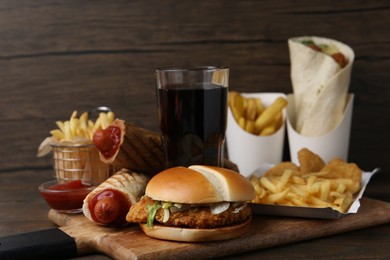 Photo of Different delicious fast food and cola on wooden table, closeup