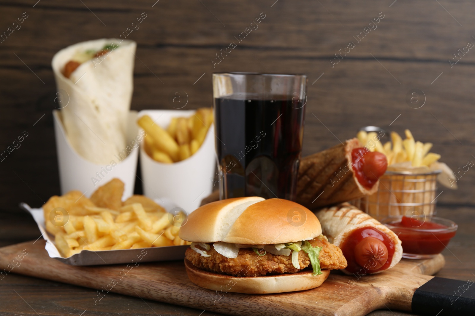 Different delicious fast food and cola on wooden table, closeup Photo of Different delicious fast food and cola on wooden table, closeup