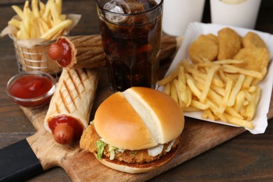Photo of Different delicious fast food and cola on wooden table, closeup