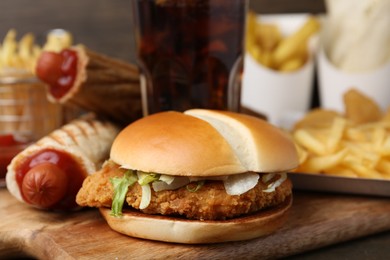 Photo of Delicious burger and other fast food on table, closeup