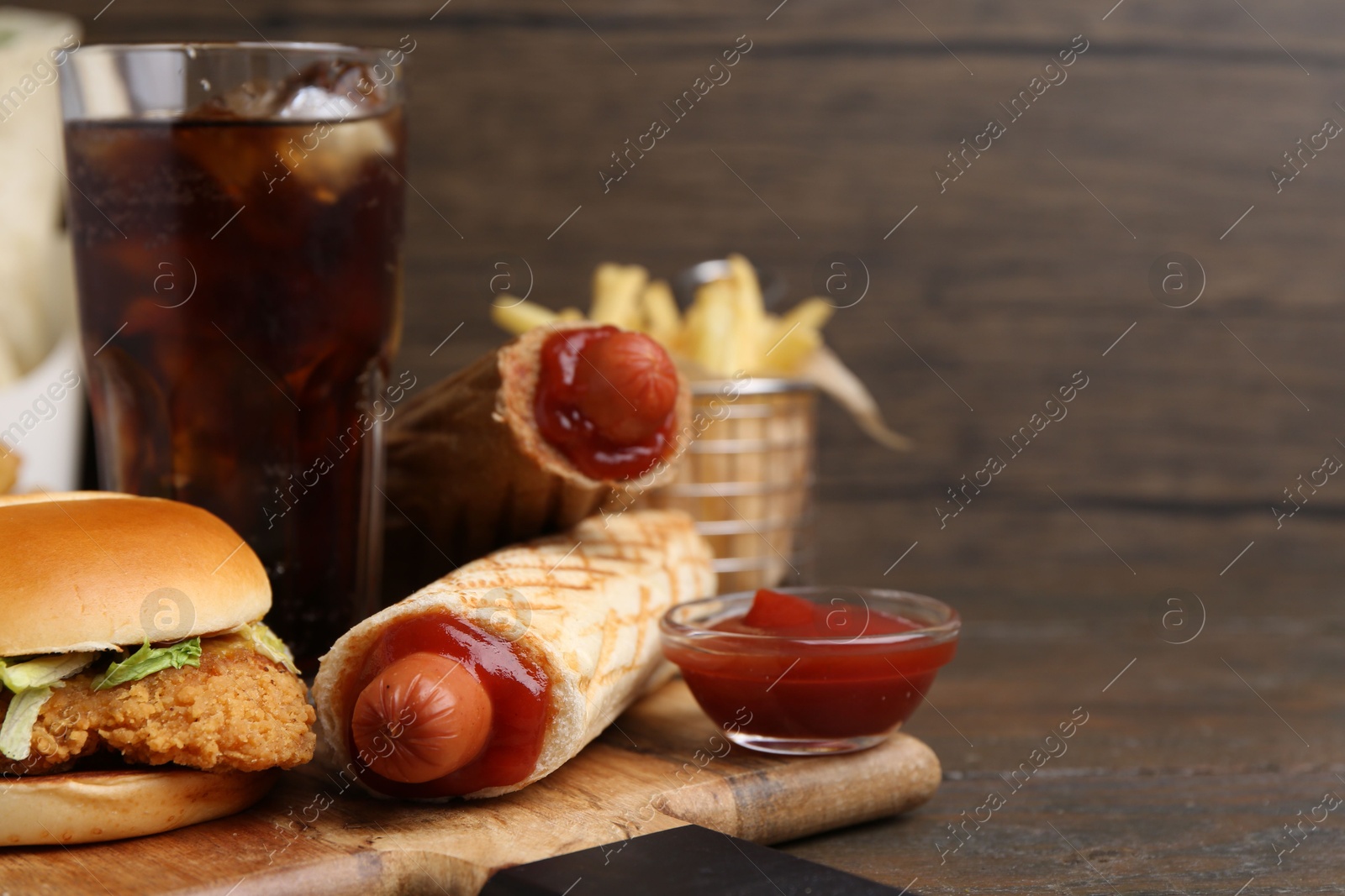 Delicious burger, cola and other fast food on wooden table, closeup. Space for text Photo of Delicious burger, cola and other fast food on wooden table, closeup. Space for text