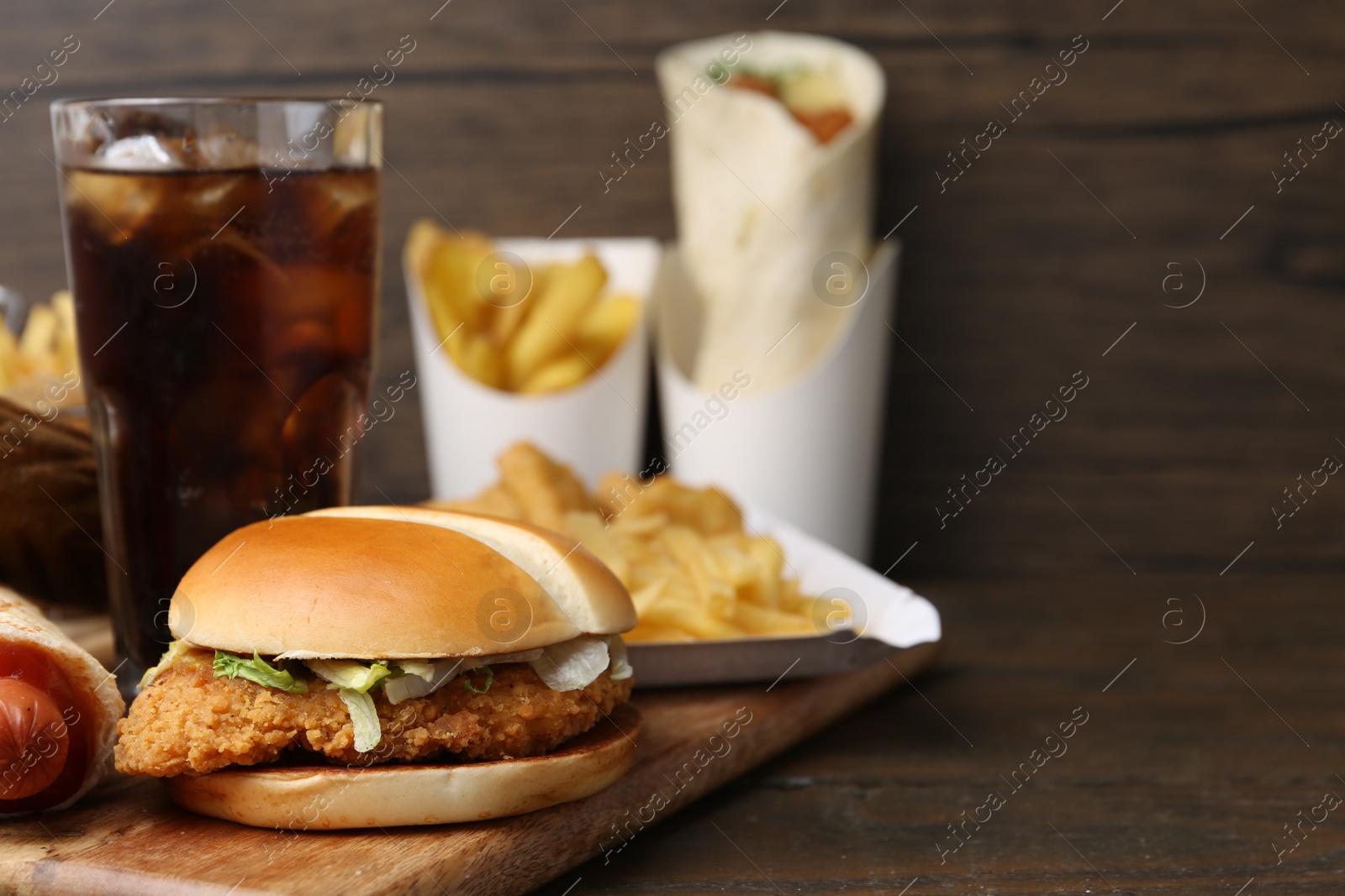 Delicious burger, cola and other fast food on wooden table, closeup. Space for text Photo of Delicious burger, cola and other fast food on wooden table, closeup. Space for text