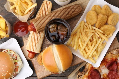 Photo of Different delicious fast food and cola on wooden table, flat lay