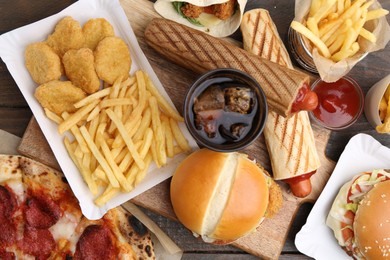 Photo of Different delicious fast food and cola on wooden table, flat lay