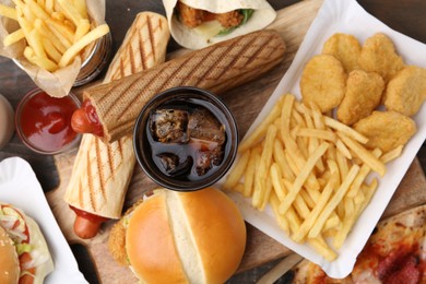 Photo of Different delicious fast food and cola on wooden table, flat lay