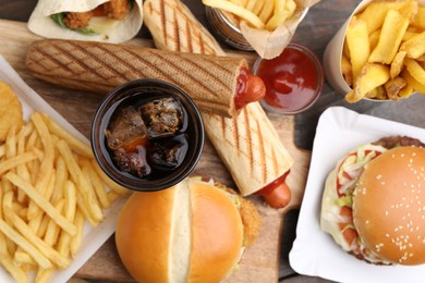 Photo of Different delicious fast food and cola on wooden table, flat lay
