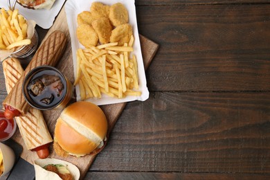 Photo of Different delicious fast food and cola on wooden table, flat lay. Space for text
