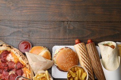 Photo of Different delicious fast food and ketchup on wooden table, flat lay. Space for text