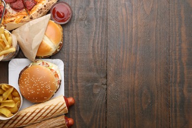 Photo of Different delicious fast food and ketchup on wooden table, flat lay. Space for text