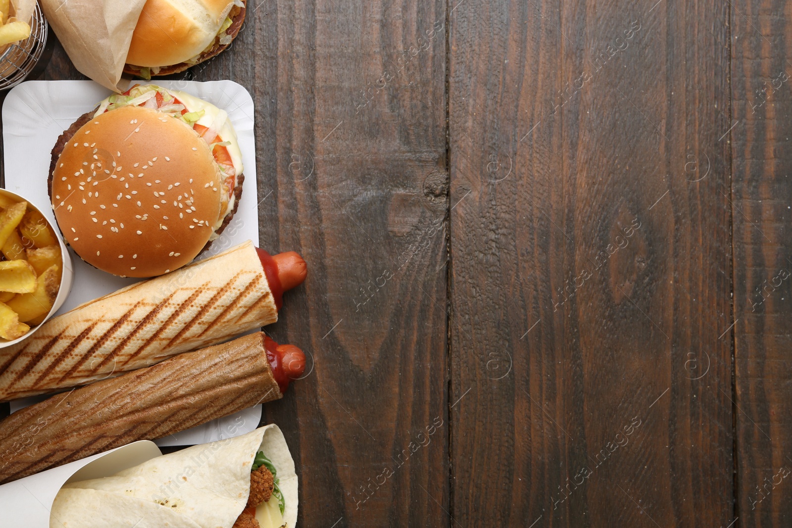 Different delicious fast food on wooden table, flat lay. Space for text Photo of Different delicious fast food on wooden table, flat lay. Space for text