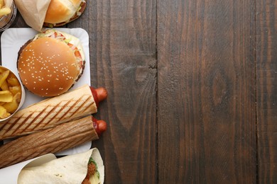 Photo of Different delicious fast food on wooden table, flat lay. Space for text