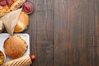 Photo of Different delicious fast food and ketchup on wooden table, flat lay. Space for text