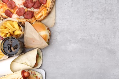 Photo of Different delicious fast food and cola on light grey textured table, flat lay. Space for text