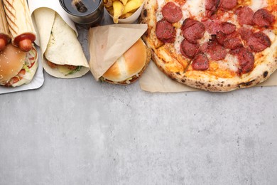 Photo of Different delicious fast food and cola on light grey textured table, flat lay. Space for text