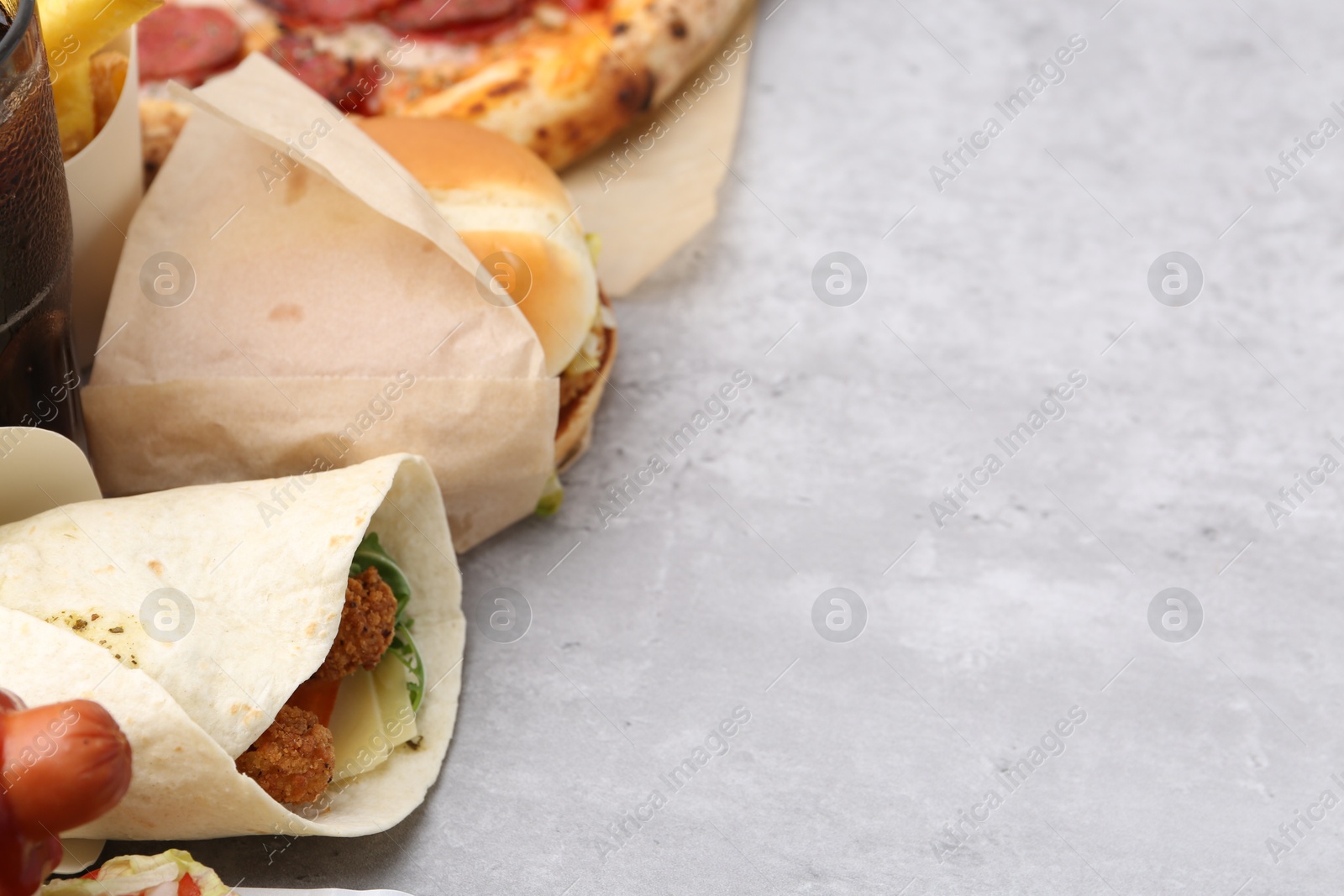 Different delicious fast food on light grey textured table, closeup. Space for text Photo of Different delicious fast food on light grey textured table, closeup. Space for text