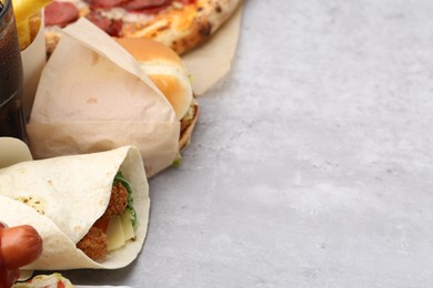 Photo of Different delicious fast food on light grey textured table, closeup. Space for text
