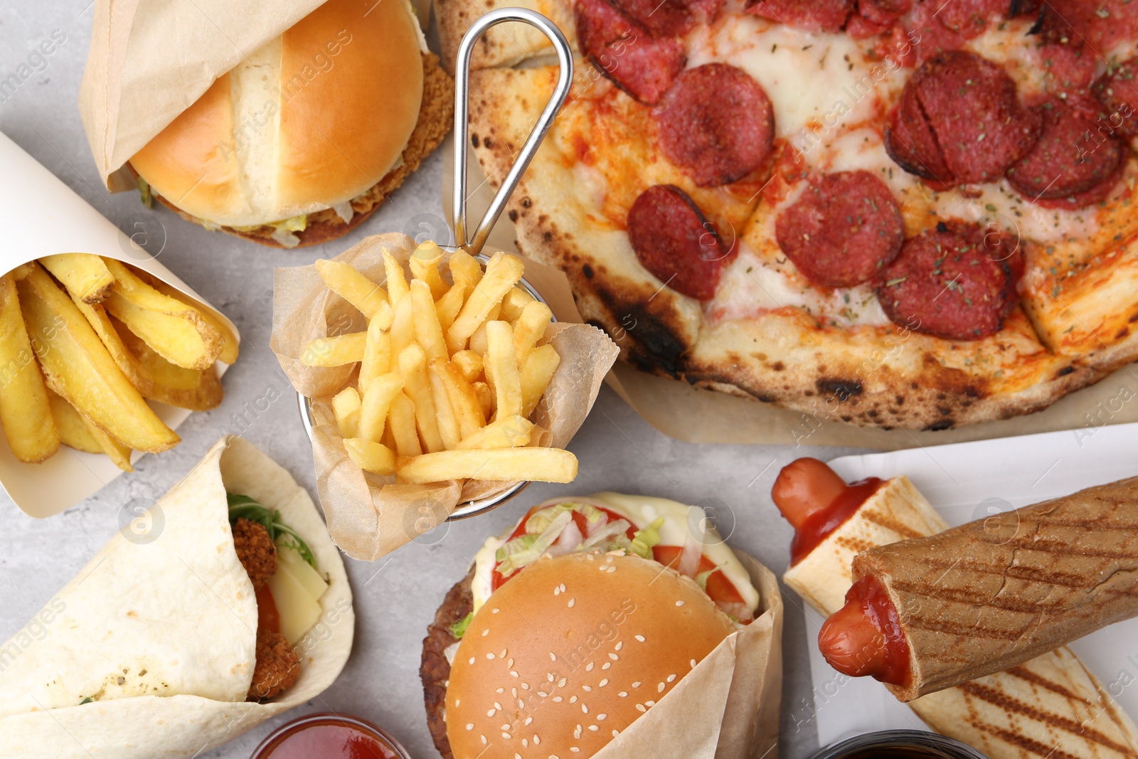 Different delicious fast food on light grey textured table, flat lay Photo of Different delicious fast food on light grey textured table, flat lay