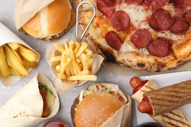 Photo of Different delicious fast food on light grey textured table, flat lay
