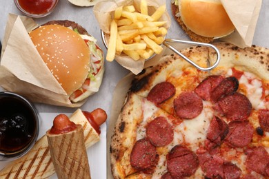 Photo of Different delicious fast food and cola on light grey table, flat lay