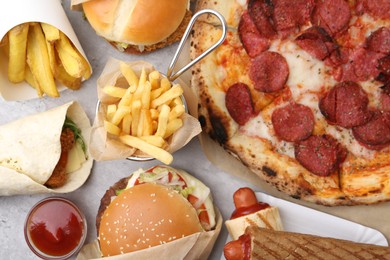 Photo of Different delicious fast food on light grey textured table, flat lay