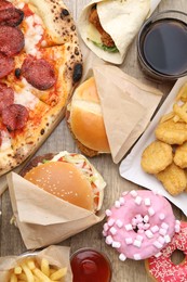 Photo of Different delicious fast food and cola on wooden table, flat lay