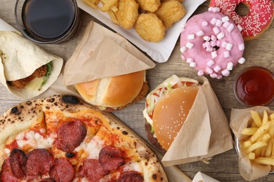 Photo of Different delicious fast food and cola on wooden table, flat lay