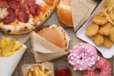 Photo of Different delicious fast food on wooden table, flat lay