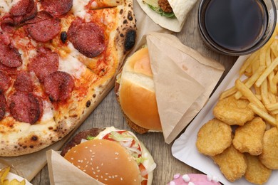 Photo of Different delicious fast food and cola on wooden table, flat lay