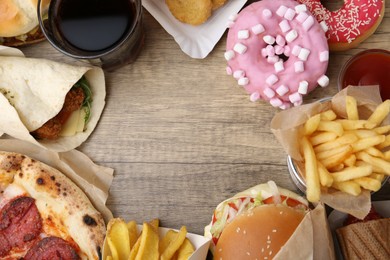 Photo of Frame of different delicious fast food and cola on wooden table, flat lay. Space for text