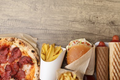 Photo of Different delicious fast food on wooden table, flat lay. Space for text