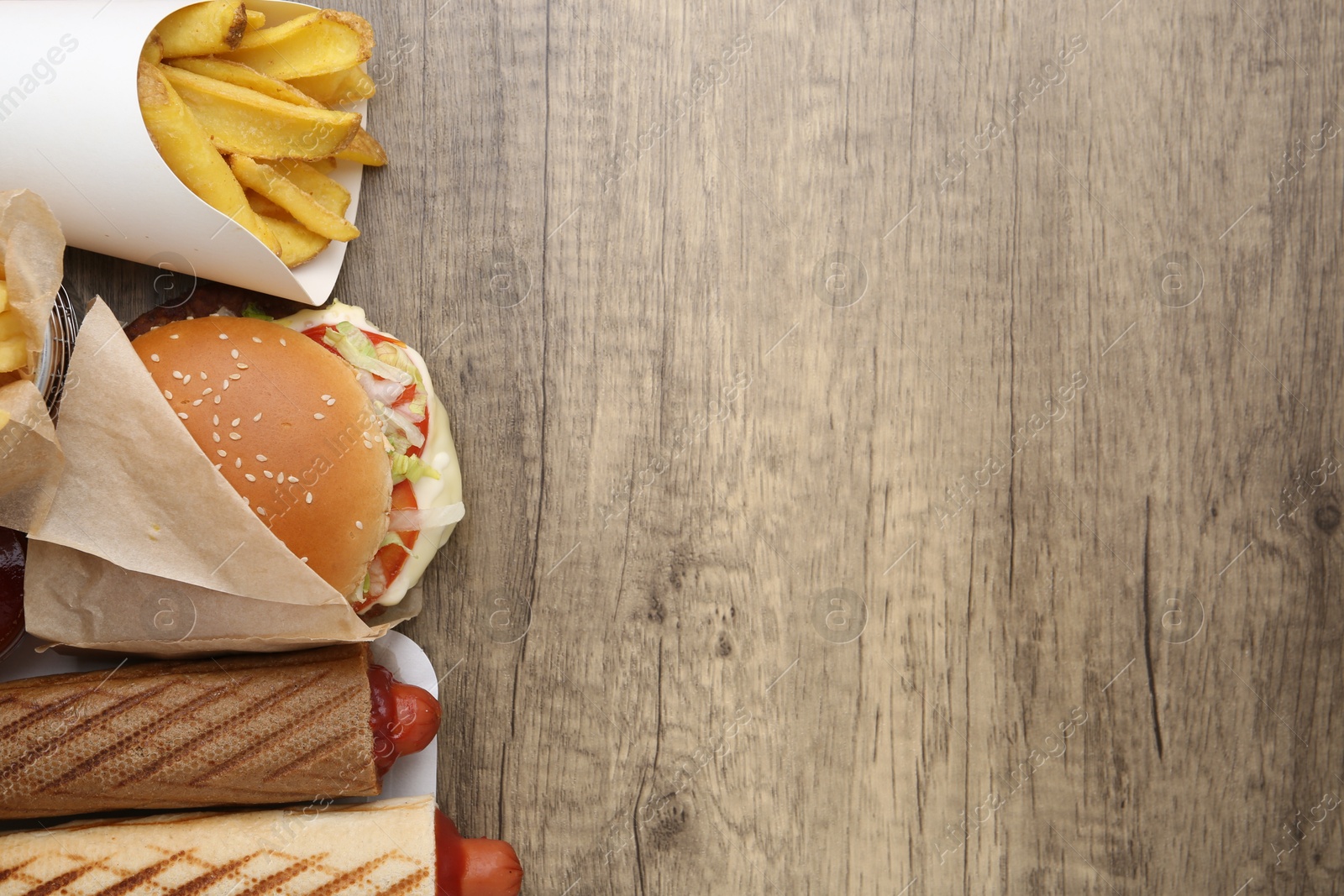 Different delicious fast food on wooden table, flat lay. Space for text Photo of Different delicious fast food on wooden table, flat lay. Space for text