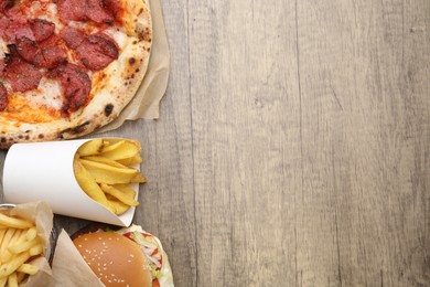 Photo of Different delicious fast food on wooden table, flat lay. Space for text