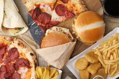 Photo of Different delicious fast food and cola on wooden table, flat lay