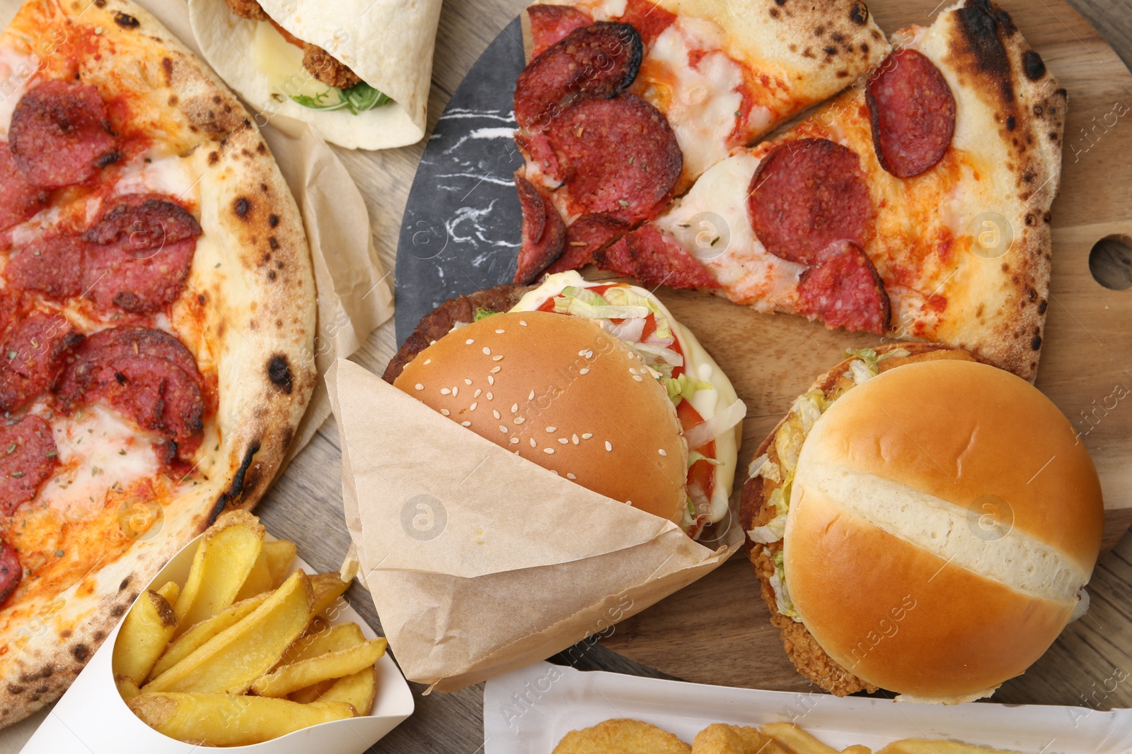 Different delicious fast food and cola on wooden table, flat lay Photo of Different delicious fast food and cola on wooden table, flat lay