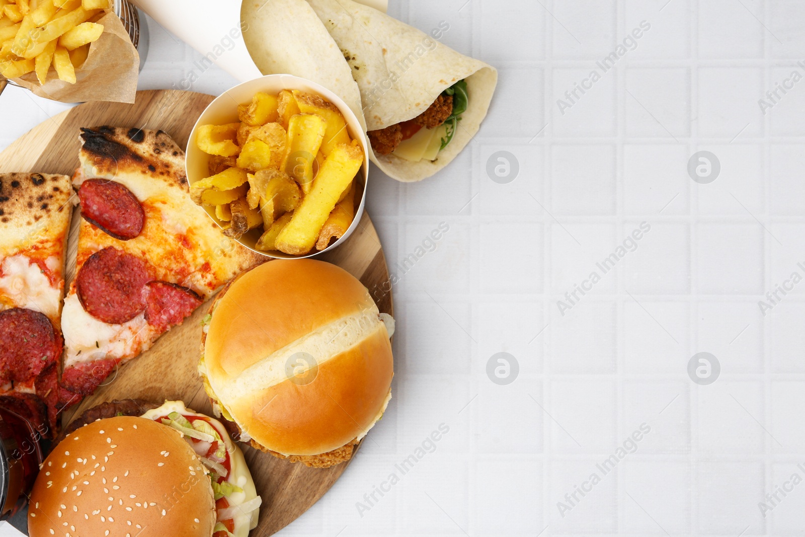 Different delicious fast food on white tiled table, flat lay. Space for text Photo of Different delicious fast food on white tiled table, flat lay. Space for text