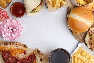 Photo of Frame of different delicious fast food, ketchup and cola on white tiled table, flat lay. Space for text
