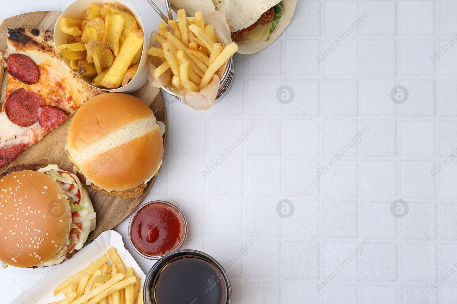 Different delicious fast food, ketchup and cola on white tiled table, flat lay. Space for text Photo of Different delicious fast food, ketchup and cola on white tiled table, flat lay. Space for text