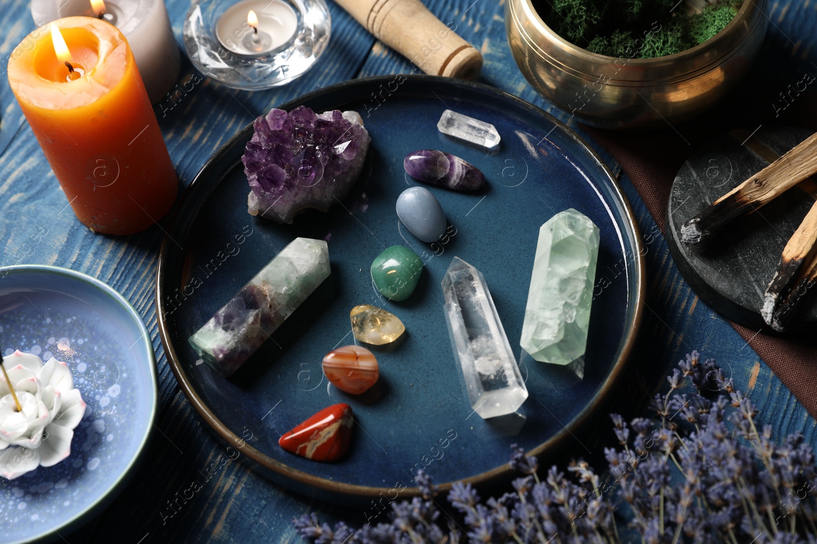 Chakra gemstones, lavender flowers, incense and burning candles on blue wooden table, closeup Photo of Chakra gemstones, lavender flowers, incense and burning candles on blue wooden table, closeup