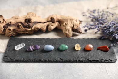Photo of Chakra gemstones and lavender flowers on light table, closeup