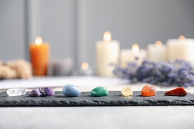 Photo of Chakra gemstones, lavender flowers and burning candles on light table, selective focus