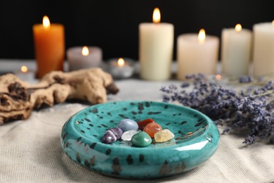 Photo of Chakra gemstones, lavender flowers and burning candles on light table, selective focus