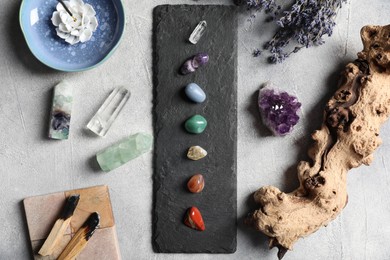 Photo of Chakra gemstones, incense and palo santo on light table, flat lay