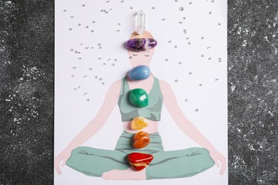 Photo of Human drawing with gemstones placed on chakras against black background, top view