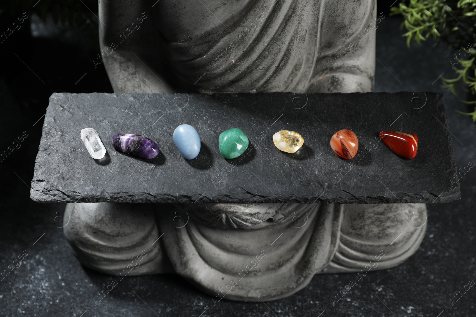 Statue with chakra gemstones on black table, closeup Photo of Statue with chakra gemstones on black table, closeup