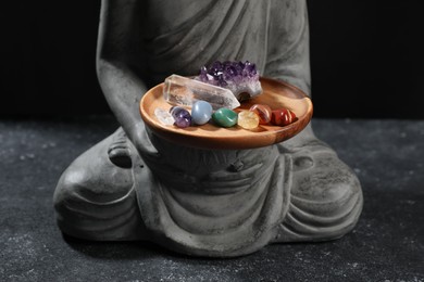 Photo of Statue with chakra gemstones on black table, closeup