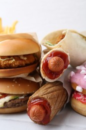 Photo of Different delicious fast food on white table, closeup