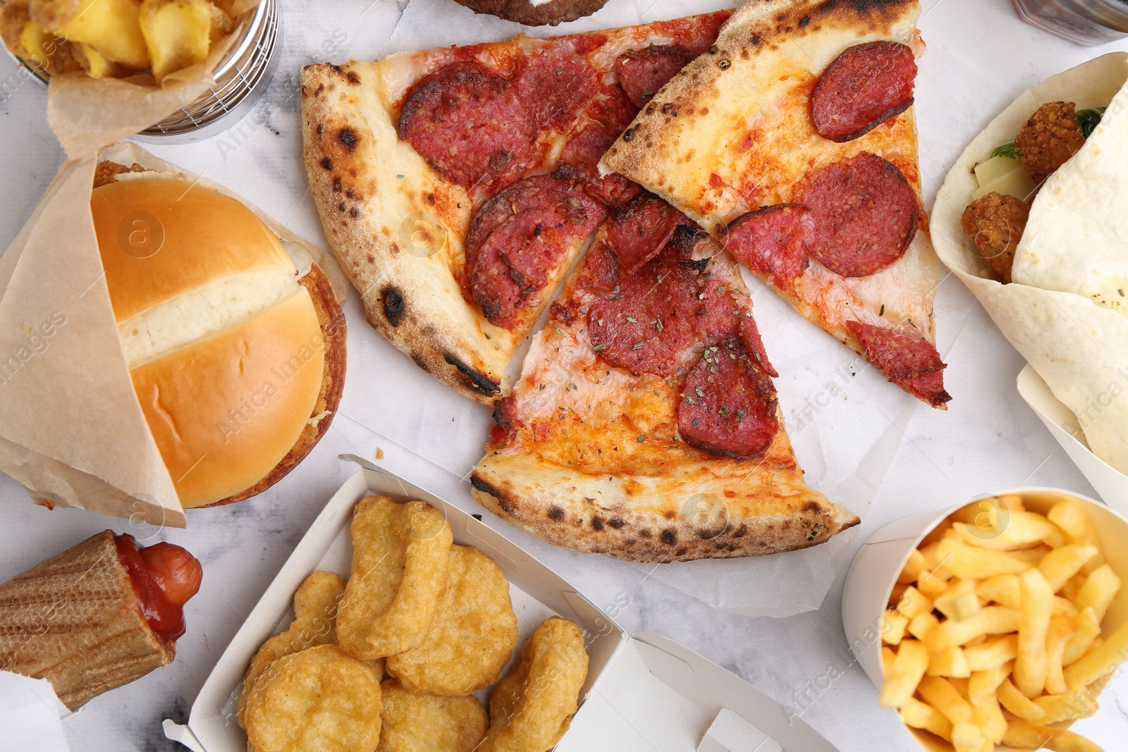 Different delicious fast food on white marble table, flat lay Photo of Different delicious fast food on white marble table, flat lay