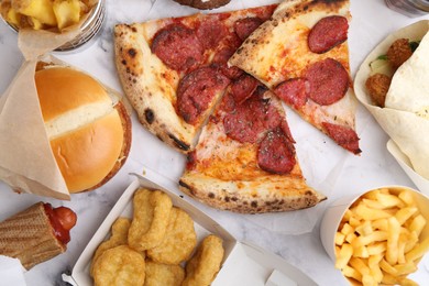 Photo of Different delicious fast food on white marble table, flat lay